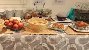 A buffet table with various food items, including fruits, pastries, and condiments, arranged on placemats.