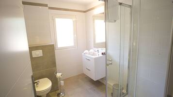 Un baño moderno con inodoro, lavamanos y ducha.