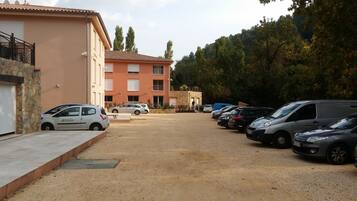 A parking lot with several cars and a building with a stone facade and a tiled roof.