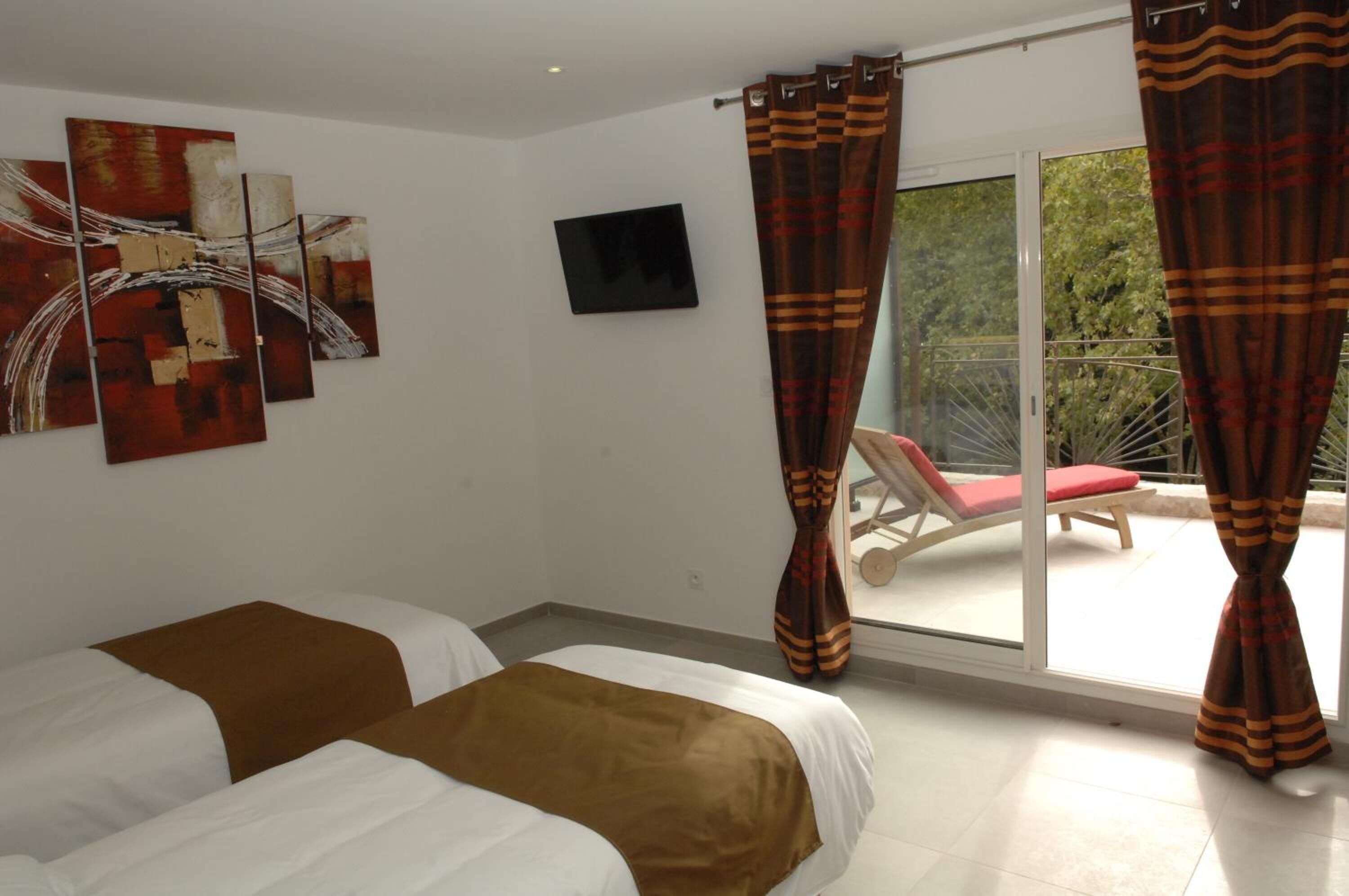 Ein Hotelzimmer mit zwei Betten, einem Fernseher und einem Balkon mit einem roten Stuhl.