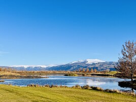 Un paisaje sereno con un lago, campos cubiertos de hierba y una montaña al fondo.