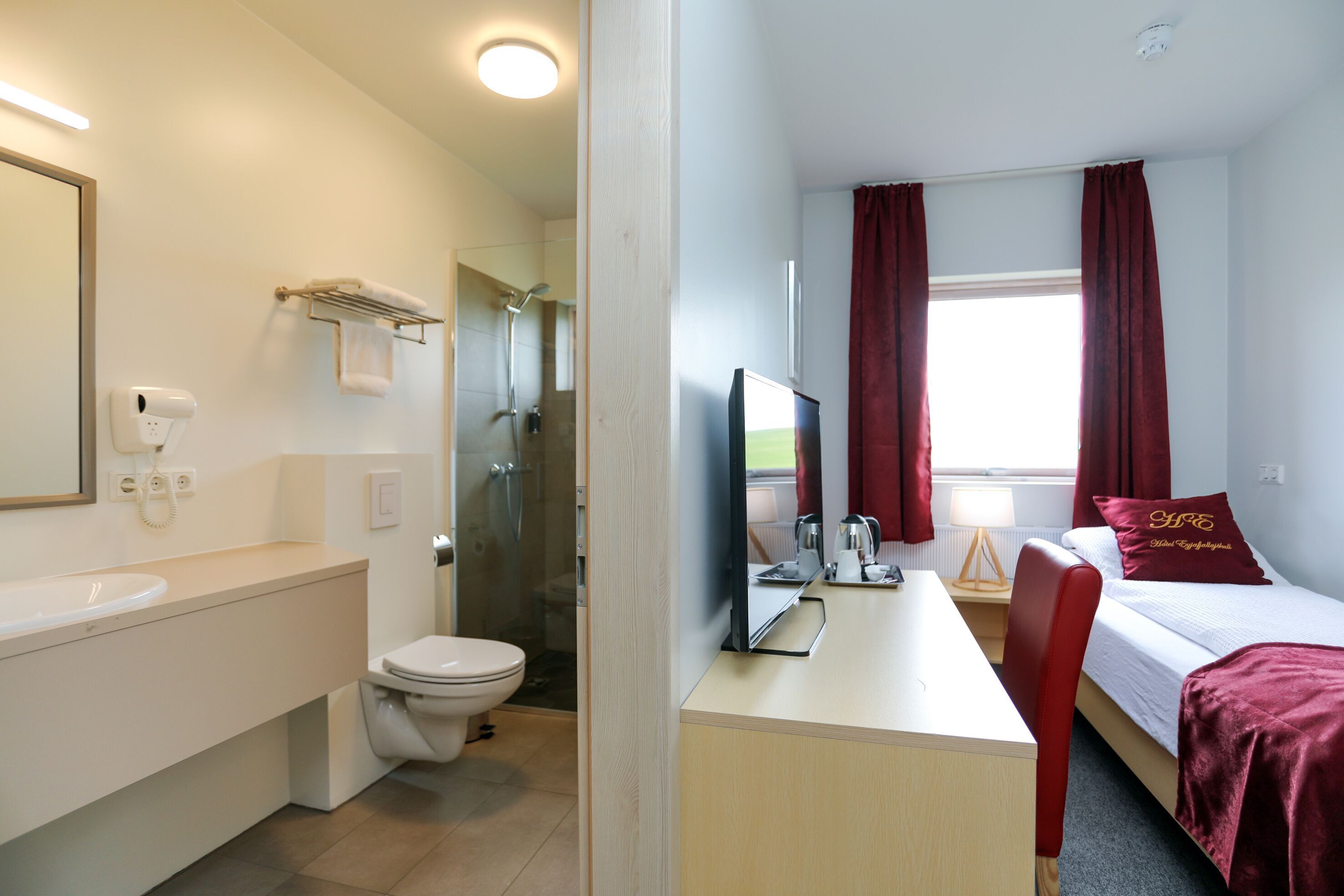 Une chambre d’hôtel comprenant une salle de bain, un lit, un bureau et un téléviseur.