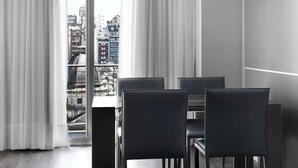 Un espace de restauration moderne avec une table et des chaises, de grandes fenêtres avec des rideaux et une vue sur le paysage urbain.