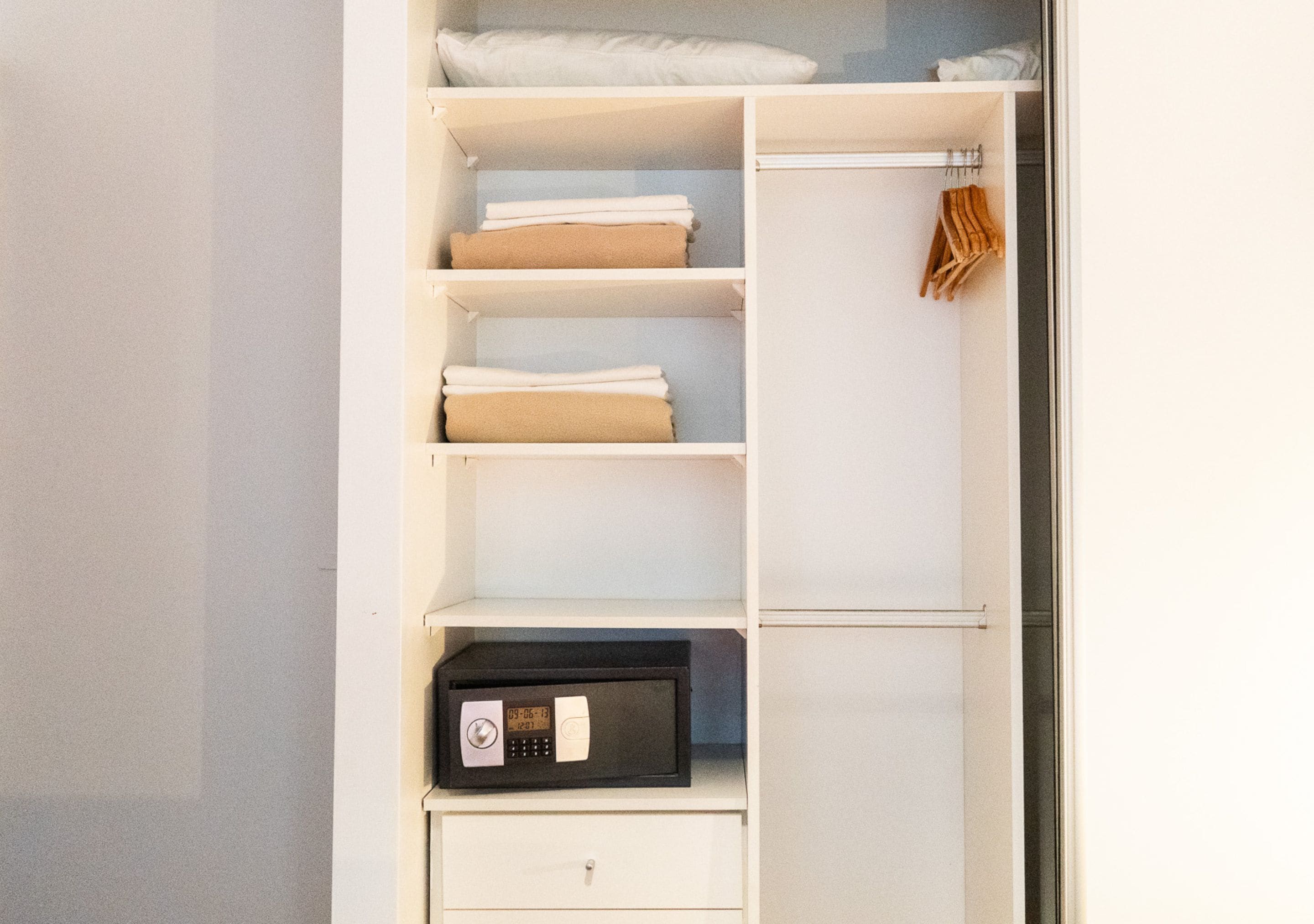 Ein weißer Kleiderschrank mit mehreren Einlegeböden, einer Kleiderstange und einer Mikrowellen-Auszugsschublade.