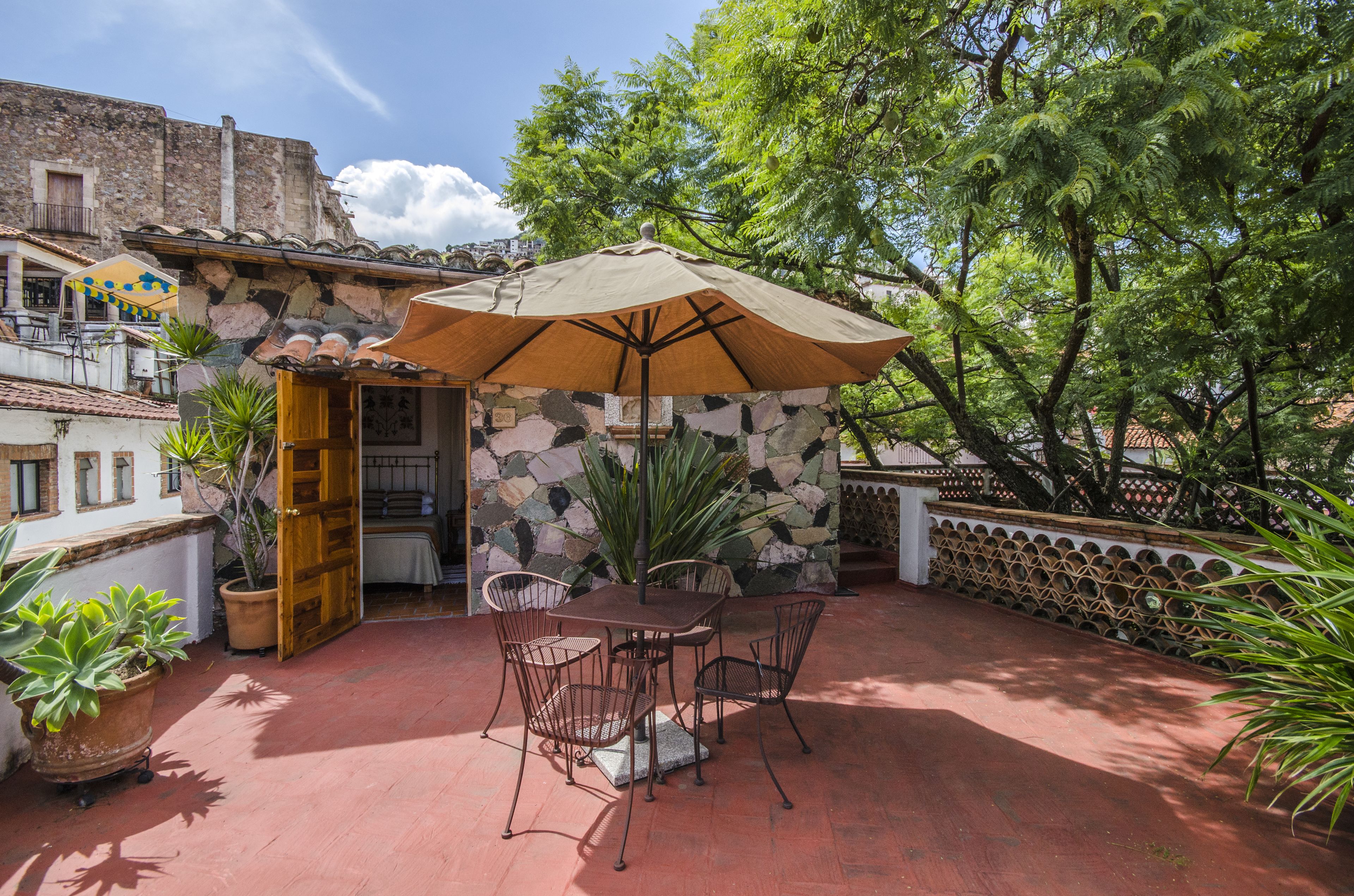 An outdoor patio with a stone wall, a wooden door, and a table with chairs.