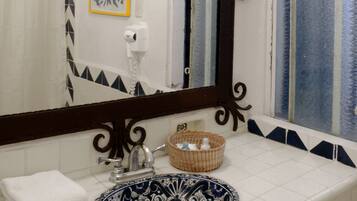 Un baño con un espejo grande, un lavabo con una pila de diseño azul y blanco, una toalla, un dispensador de jabón y una cesta decorativa.