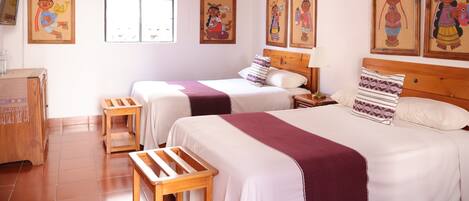 A hotel room with two beds, wooden furniture, a window, and wall art.