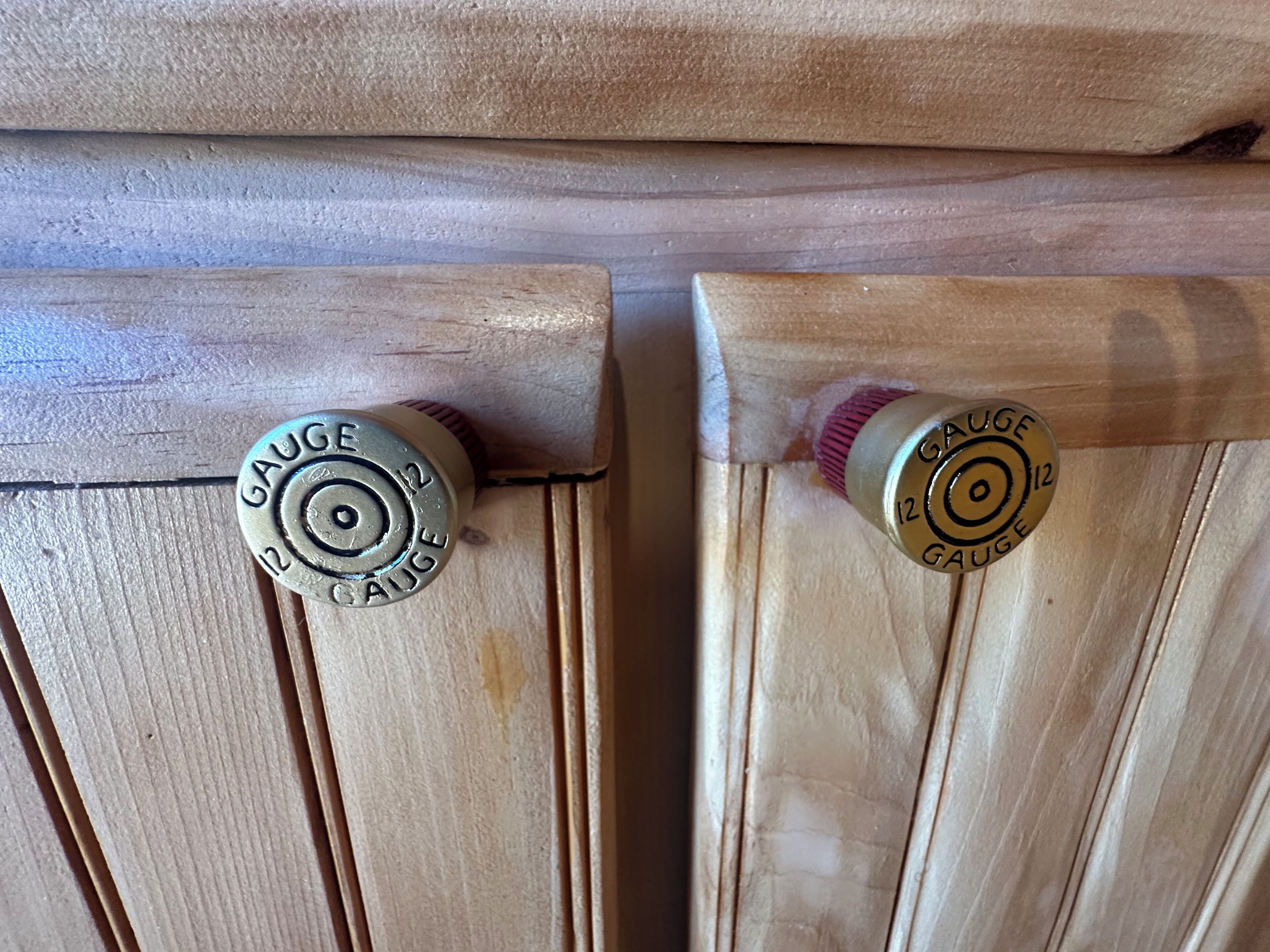 Deux portes en bois, dotées de poignées en laiton, portant l’inscription « CALIBRE 12 ».