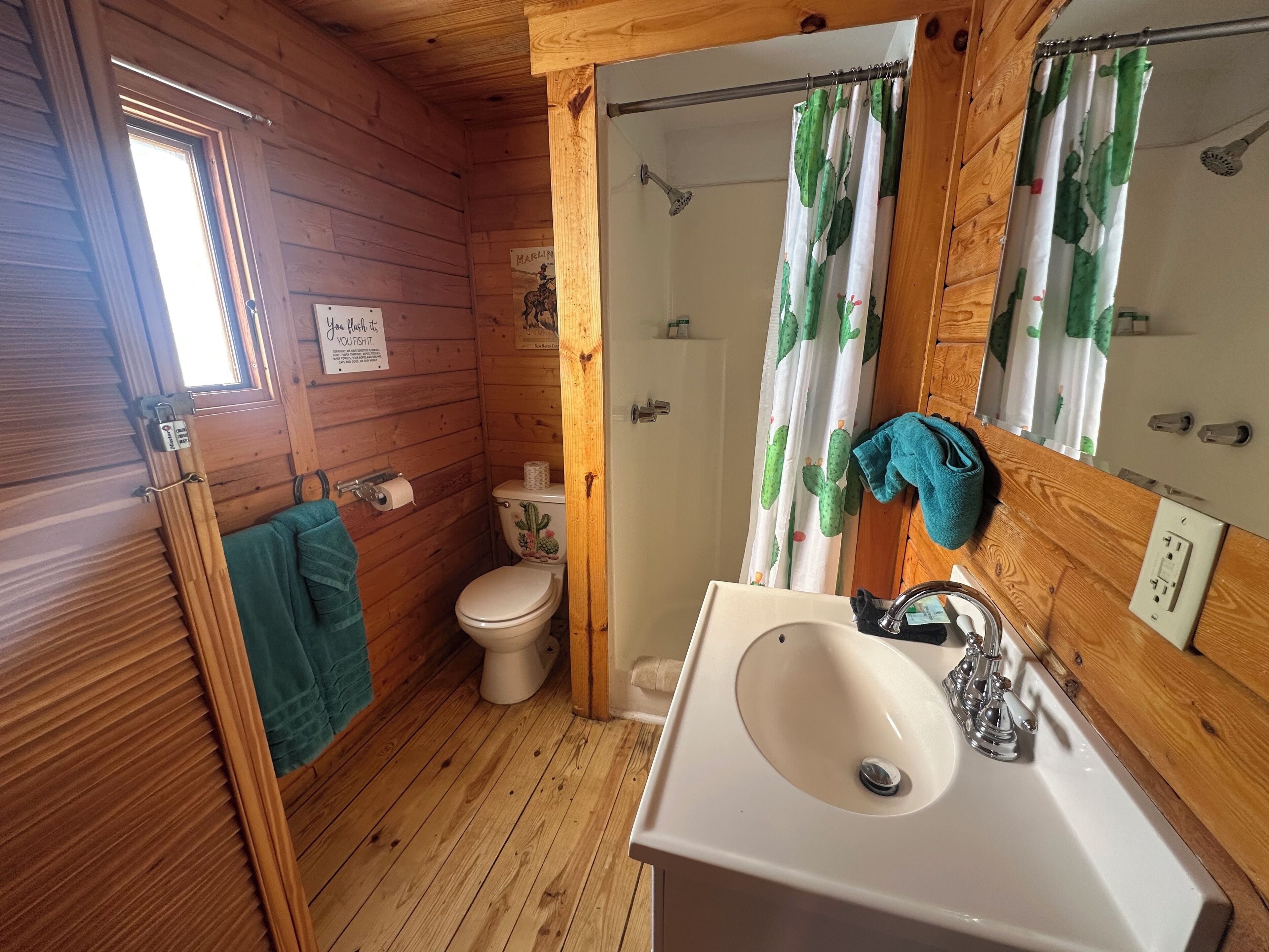 Un baño rústico de cabaña con inodoro, lavabo y ducha.