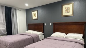 Habitación de hotel con dos camas, paredes oscuras y cuadros enmarcados.