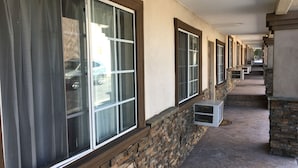 Un pasillo con amplias ventanas, paredes de piedra y unidades de aire acondicionado.