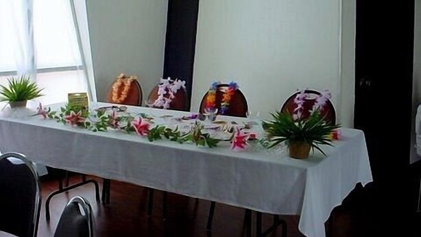 A conference table with floral decorations and potted plants, surrounded by chairs. - Ken-Bar Lodge (Gilbertsville)