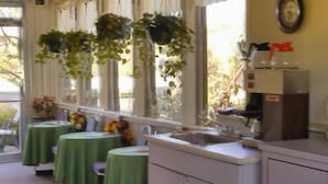 A kitchen with green tablecloths, a sink, and hanging plants. - Ken-Bar Lodge (Gilbertsville)