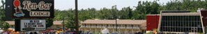 A Ken-Bar Lodge sign with a beach scene, a parking lot, and a motel building in the background. - Ken-Bar Lodge (Gilbertsville)