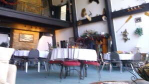 A dining area with tables and chairs, a fireplace, and decorative wall hangings. - Ken-Bar Lodge (Gilbertsville)