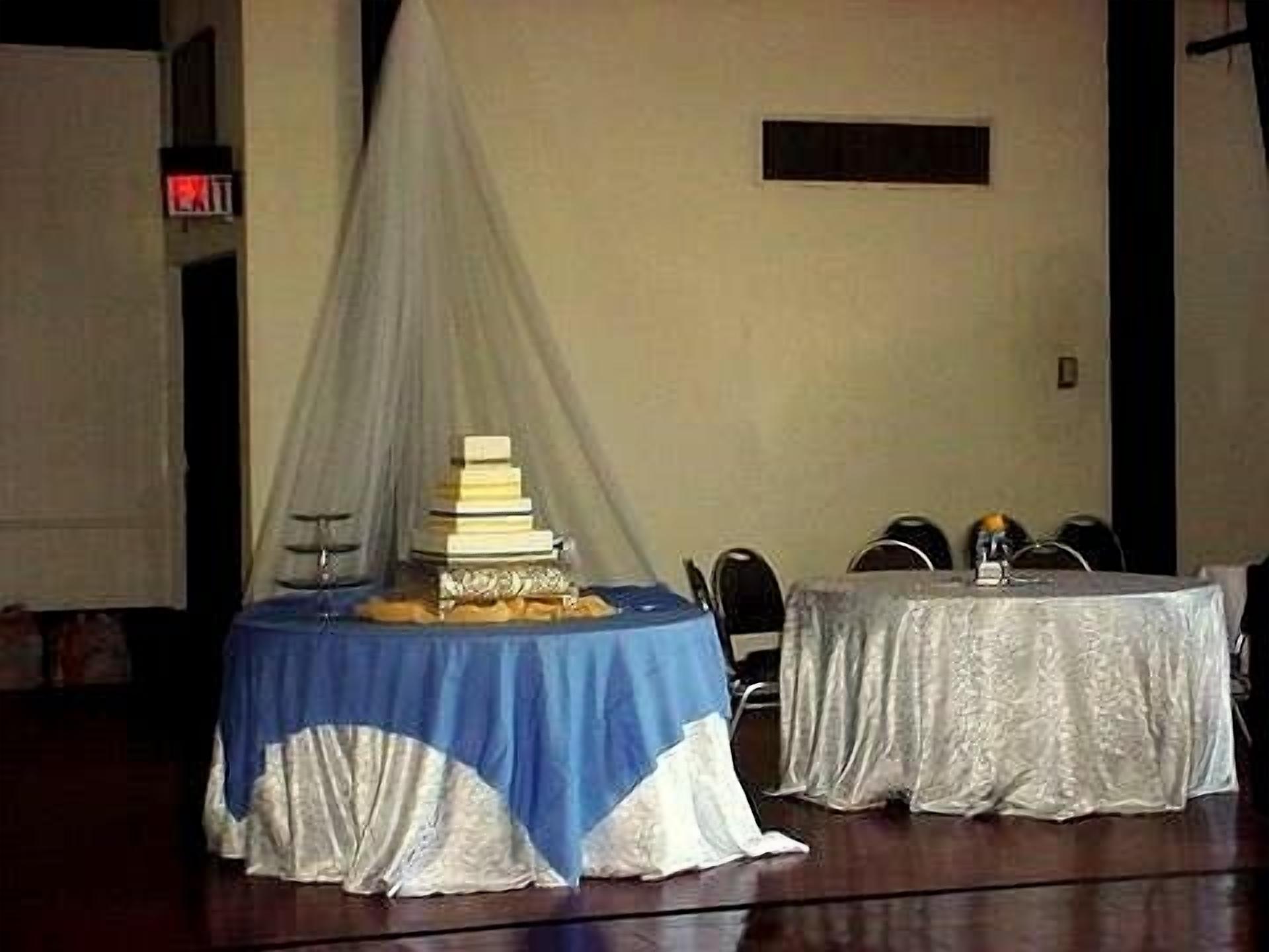 Una habitación con una mesa cubierta por un mantel azul y blanco, una silla blanca y una lámpara de mesa.