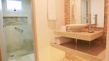 Un baño con ducha envuelta en vidrio, un lavamanos grande con encimera de mármol y un espejo con un revestimiento de madera.