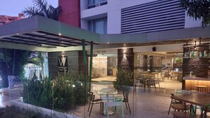A modern hotel with a glass-enclosed patio area featuring outdoor seating and a bar.