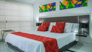 A modern hotel room with a large bed, a bedside table, a lamp, and abstract art on the wall.