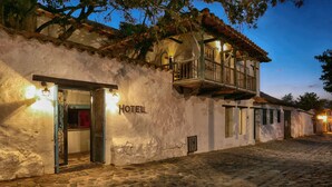 Un hotel con fachada de piedra, un balcón y un cartel con su nombre.