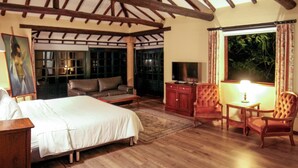 Un dormitorio con una cama grande, un sofá, un televisor y un escritorio con una lámpara.