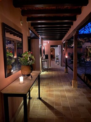 A corridor with a tiled floor, a table with a candle, and a potted plant. - Hotel Plazuela de San Agustín (Villa de Leyva)
