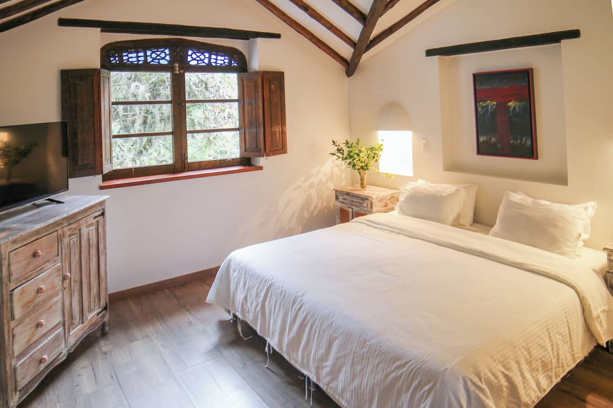 Un dormitorio con una cama grande, un armario de madera y una ventana con persianas.
