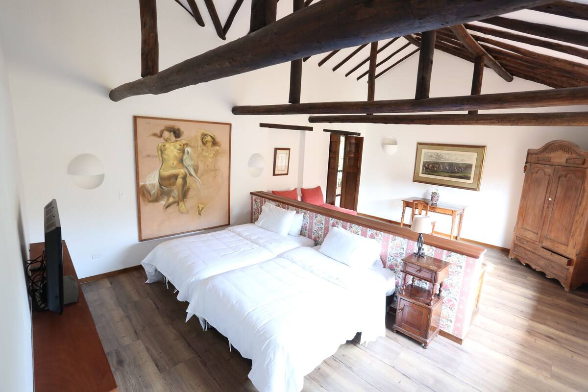Un dormitorio con una cama grande, vigas de madera, un armario de madera y un cuadro en la pared.
