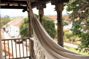 A hammock hanging between wooden pillars, overlooking a street with buildings and greenery. - Hotel Plazuela de San Agustín (Villa de Leyva)