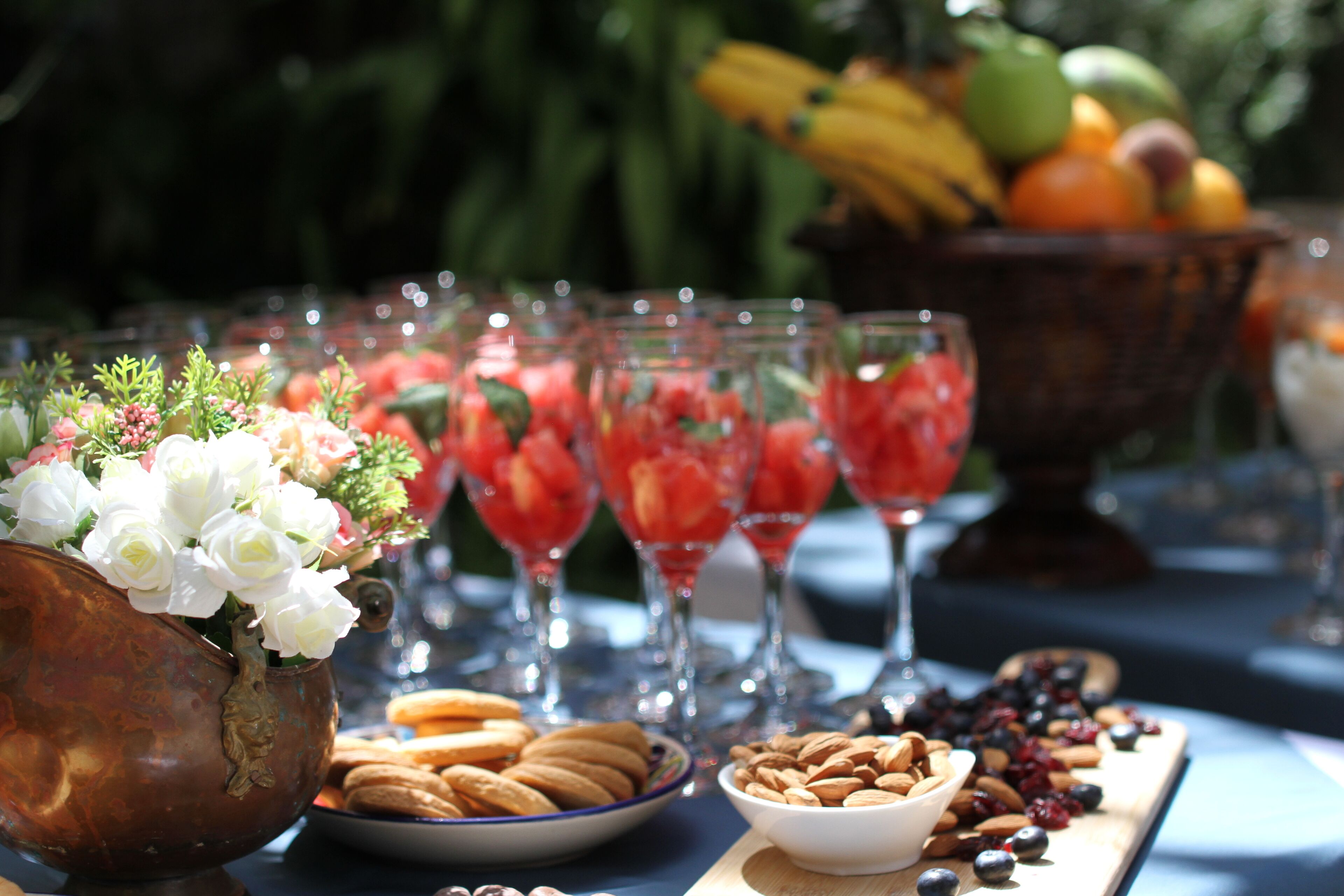 A table set with a variety of food items including a bowl of almonds, a plate of cookies, and a bowl of berries.