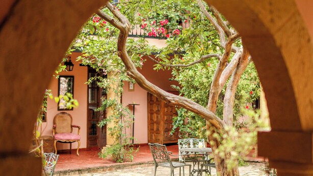 Un patio exterior con suelo de piedra, una puerta de madera y una mesa con sillas.