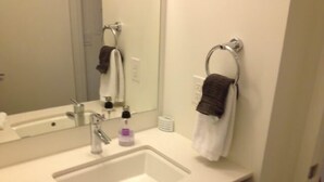 Ein Badezimmer mit einem weißen Waschbecken, einem Spiegel und zwei Handtüchern, die an Handtuchringen hängen.