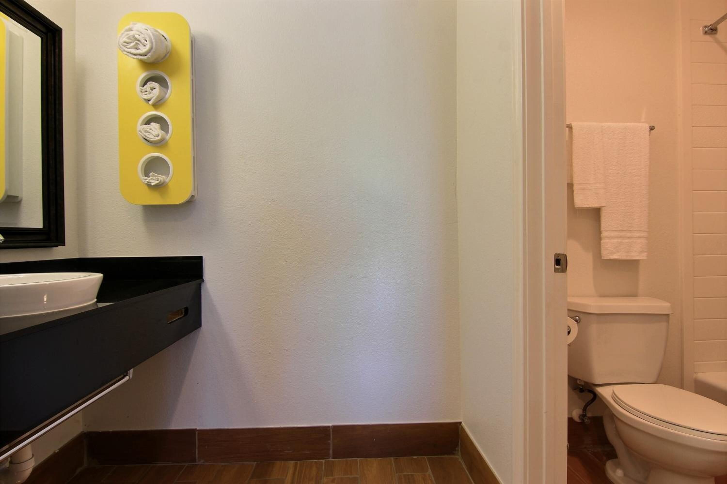Un bagno con il water bianco, un lavandino con piano nero e uno specchio con cornice nera.