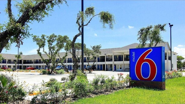 A motel with a large '6' sign, multiple-story buildings, and a parking lot.