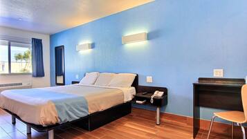 A hotel room with a bed, a desk, a chair, and a window with curtains.