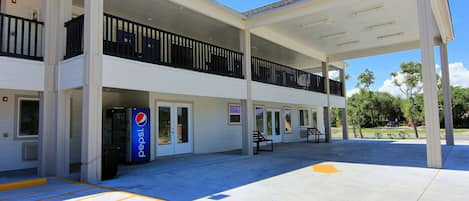 A two-story building with a covered outdoor area, a Pepsi vending machine, and a clear sky.
