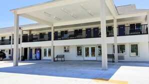 A motel with a covered parking area, multiple balconies, and a Pepsi sign.