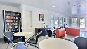 A clean, modern waiting area with vending machines, a coffee station, and seating.