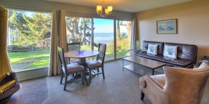 A room with a dining table and chairs, a sofa, a coffee table, and a view of the ocean. - Ocean Crest Resort (Moclips)