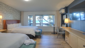 Una habitación de hotel con dos camas, un escritorio y vista al océano.