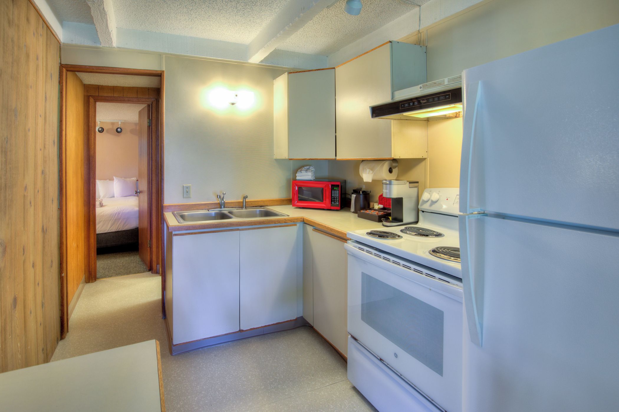 A compact kitchen with a sink, a microwave, a stove, and a refrigerator.