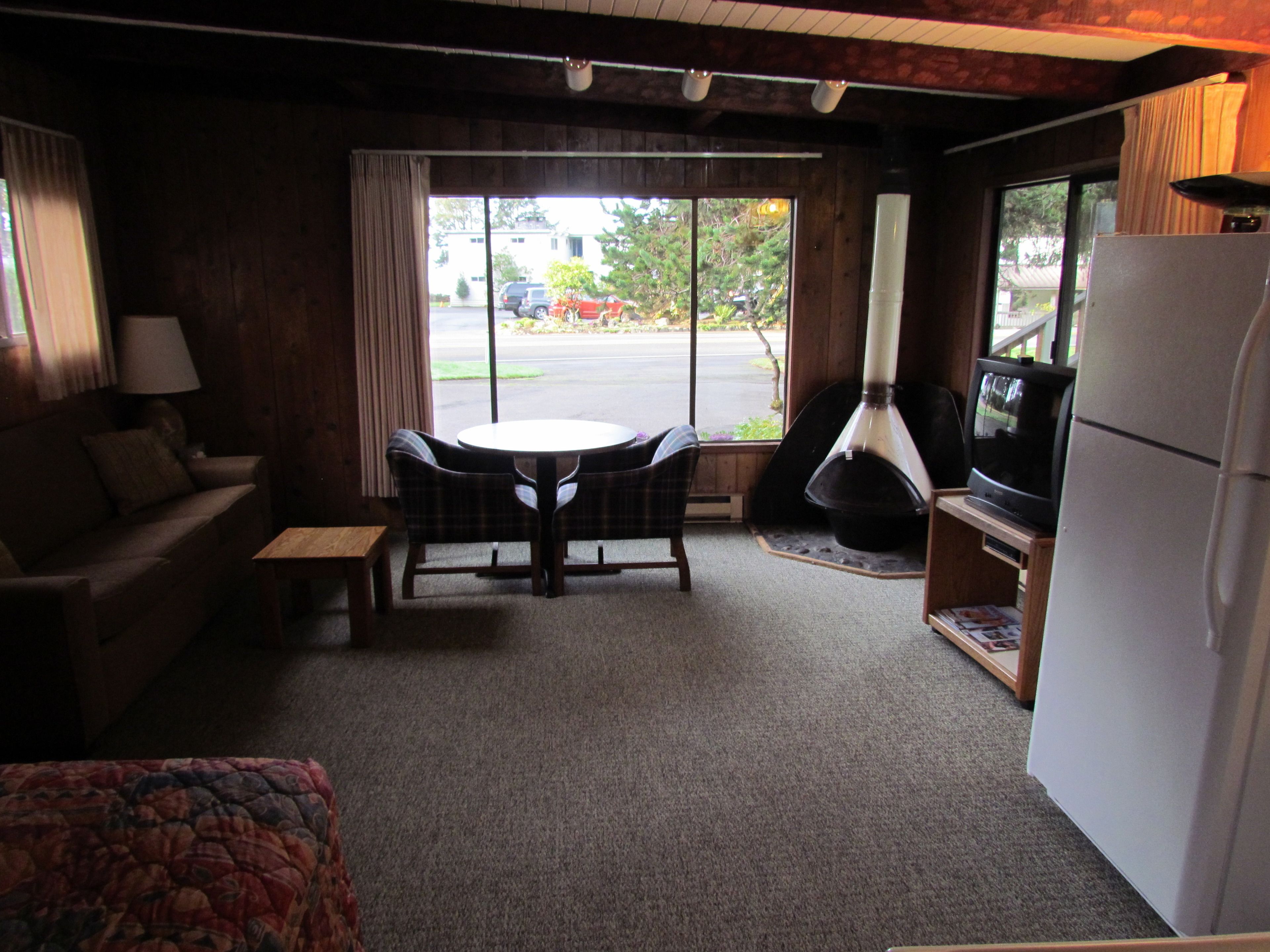 A cozy living room with a sofa, a small table, a fireplace, and a television.