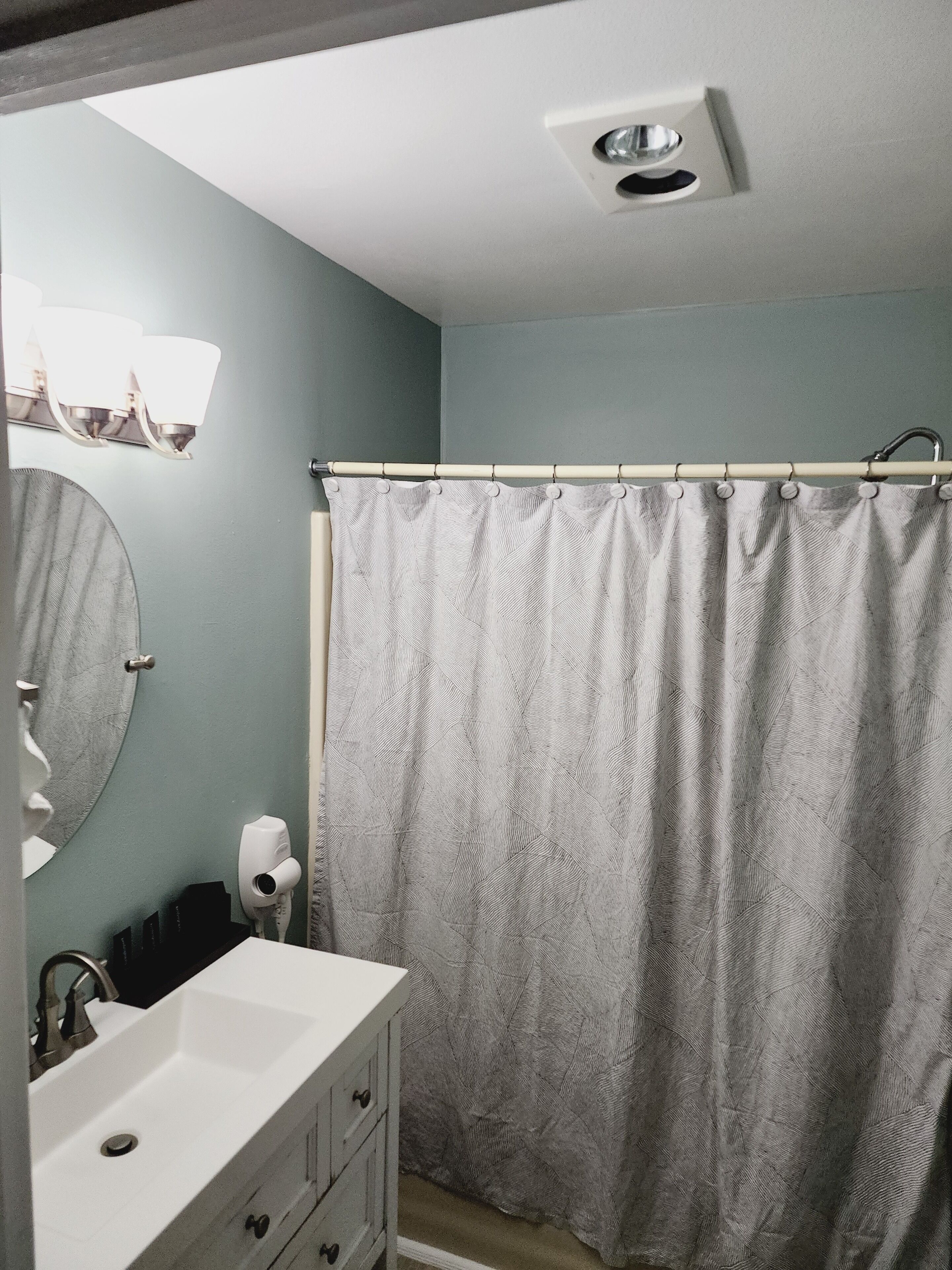 A bathroom with a white sink, a mirror, a towel rack, and a shower curtain.