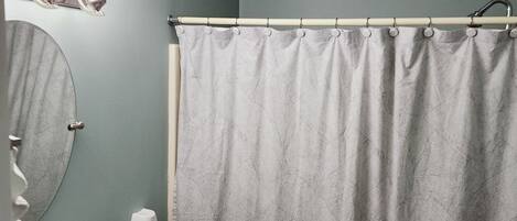 A bathroom with a white sink, a mirror, a towel rack, and a shower curtain.
