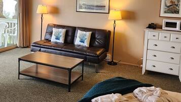 A hotel room with a leather sofa, a wooden coffee table, a white dresser, and two lamps.