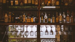 Un bar con estantes llenos de botellas de licor y copas de vino colgando.