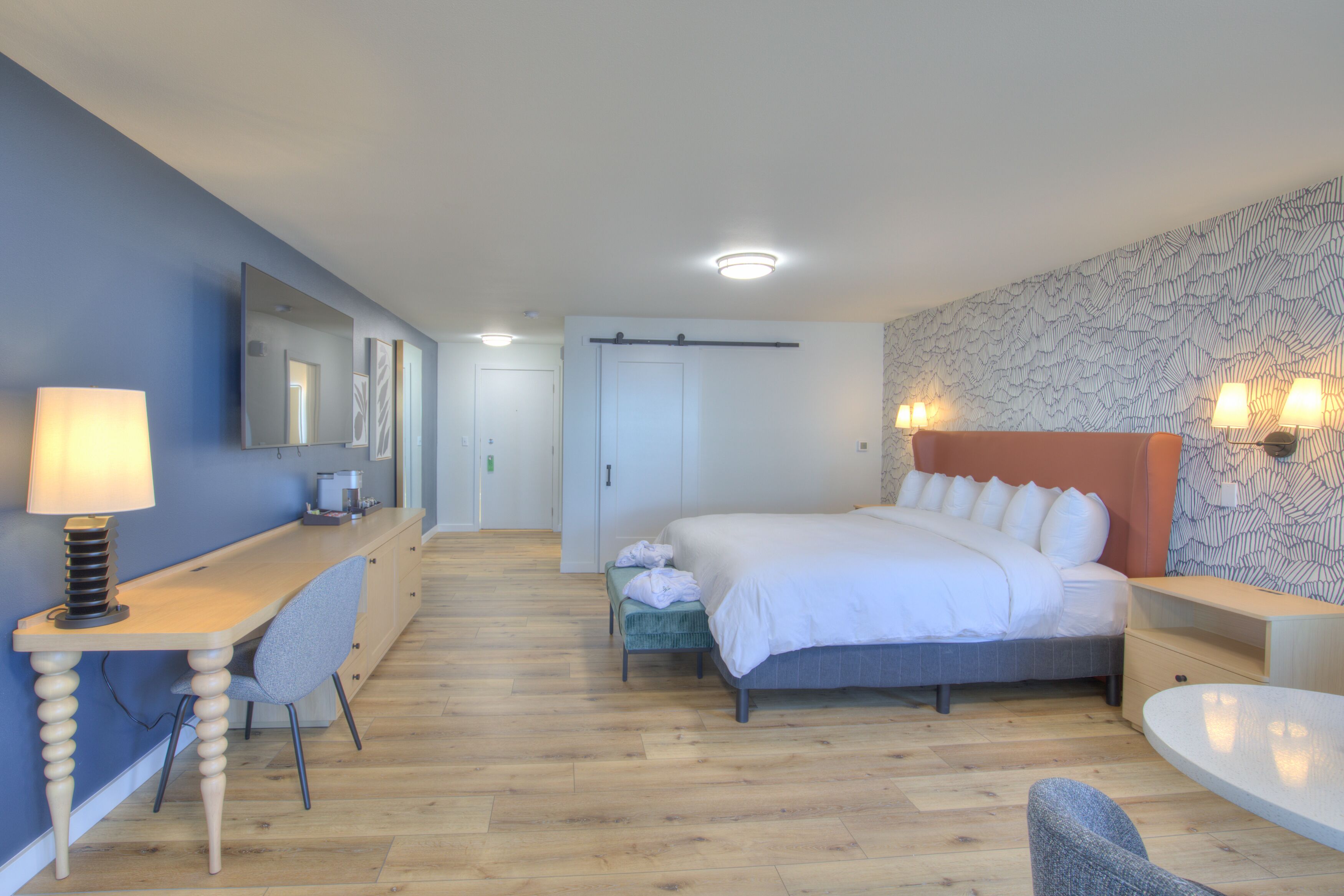 Una habitación de hotel moderna con cama, escritorio, silla y una mesita.