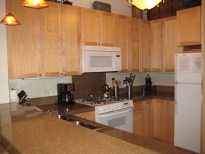 A kitchen with wooden cabinets, a microwave, a stove, and a refrigerator.