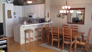 A kitchen with a dining area, wooden chairs, a central island, and a ceiling fan. - Chateau Sans Nom by Mammoth Reservation Bureau (Mammoth Lakes)