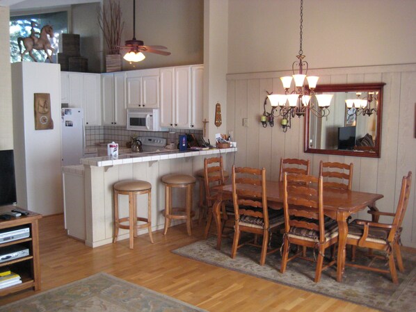 A kitchen with a dining area, wooden chairs, a central island, and a ceiling fan.